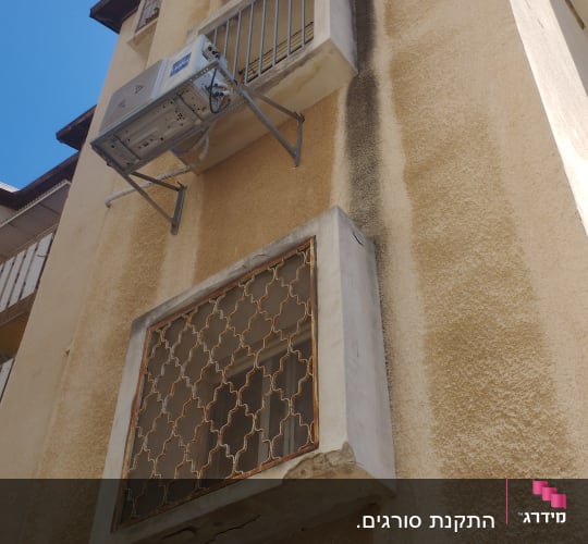 מסגרת מתכת על חלון בניין עם מזגנים